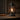Close-up of rustic electric lantern table lamp with glowing Edison-style bulb on a wood surface