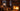 Electric lantern table lamp on a table in a log cabin living room with a fireplace and snow outside